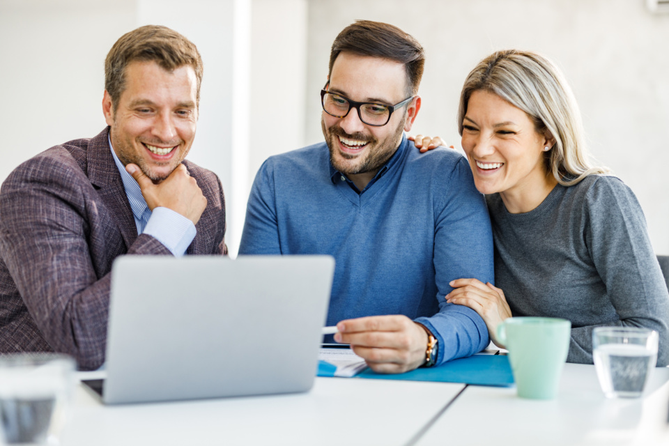 Happy couple and their insurance agent using laptop in the office 1250622576 2125x1416