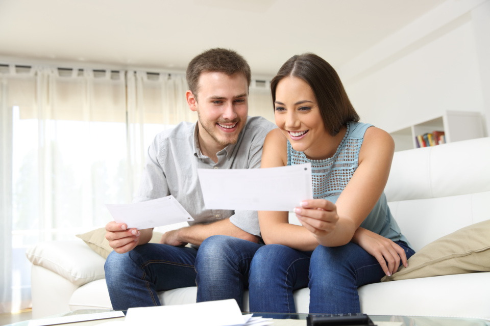 Happy couple looking and checking bills at home 1219963854 2125x1416