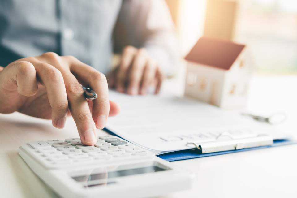 Home agents are using a calculator to calculate the loan period each month for the customer 1075993466 2125x1416