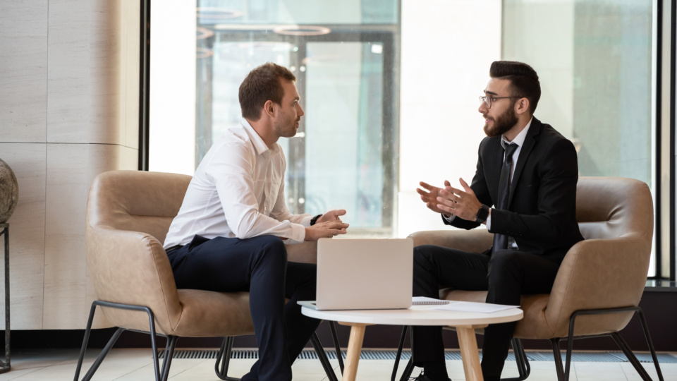 Middle eastern and caucasian ethnicity businessmen talking negotiating indoors 1186185280 2313x1301